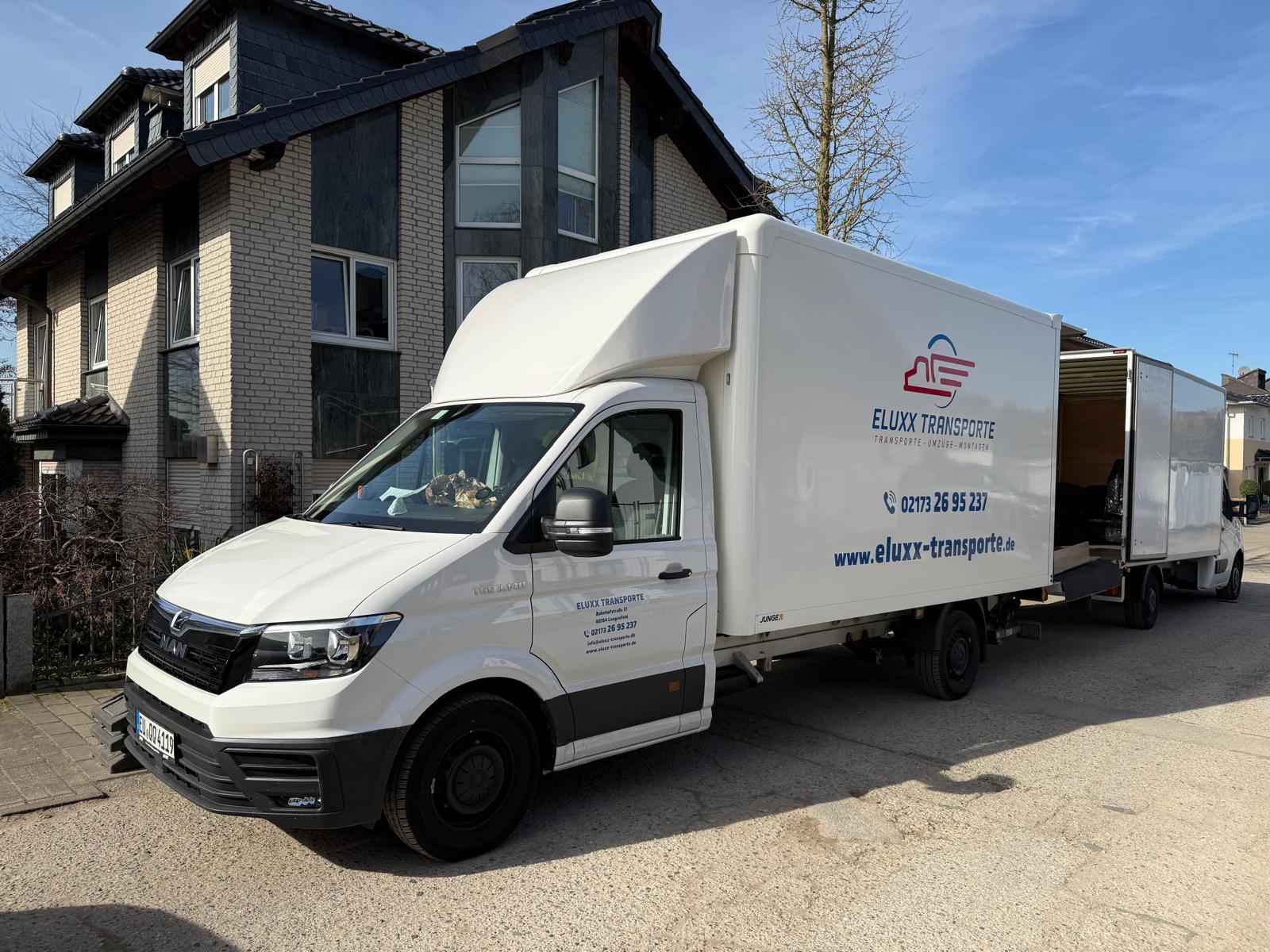 Zwei Umzugswagen vor modernem Einfamilienhaus