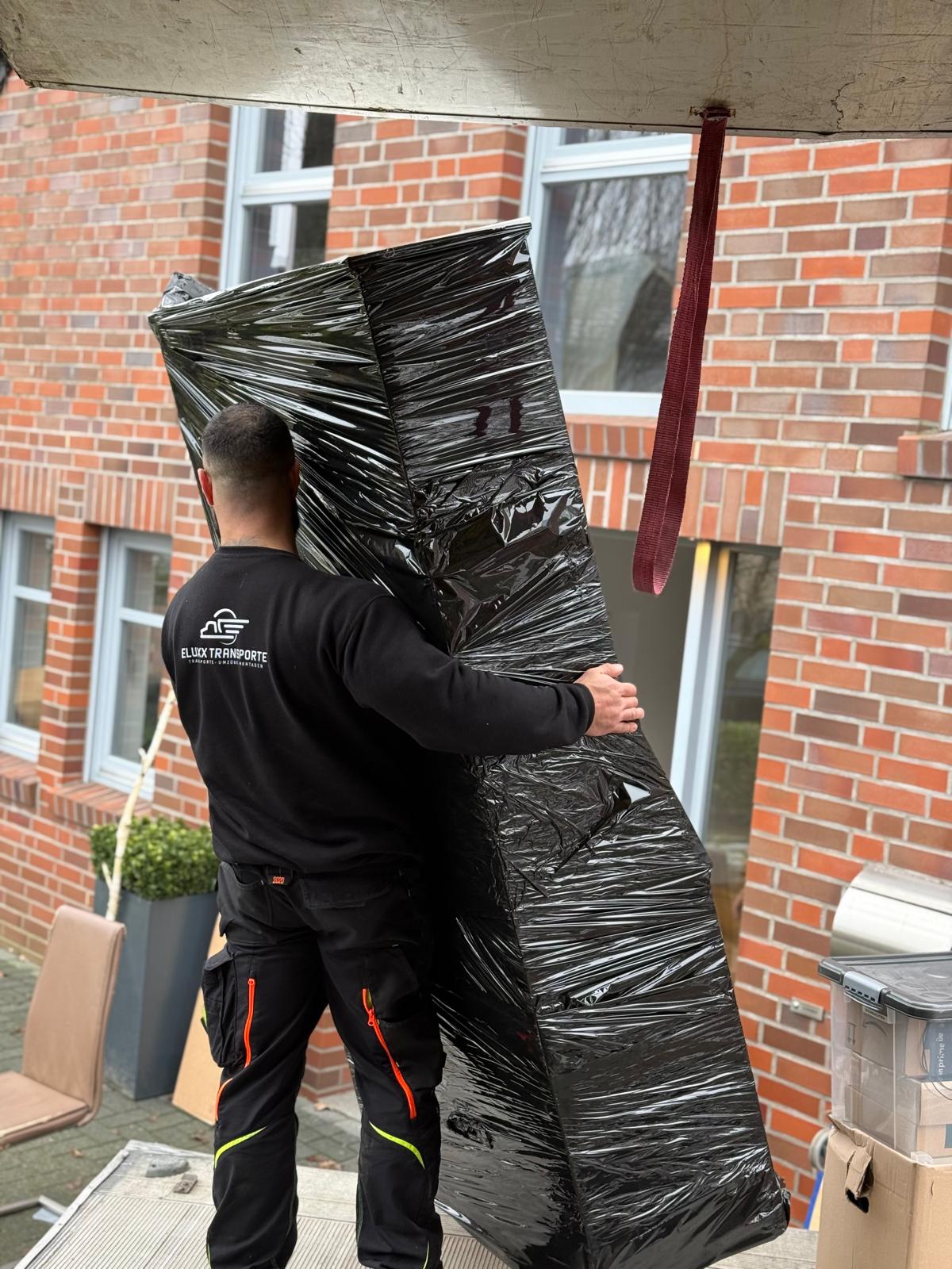 Mitarbeiter trägt sorgfältig verpacktes Möbelstück
